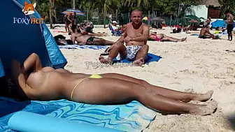 Sunbathing topless on the beach to be watched by other guys